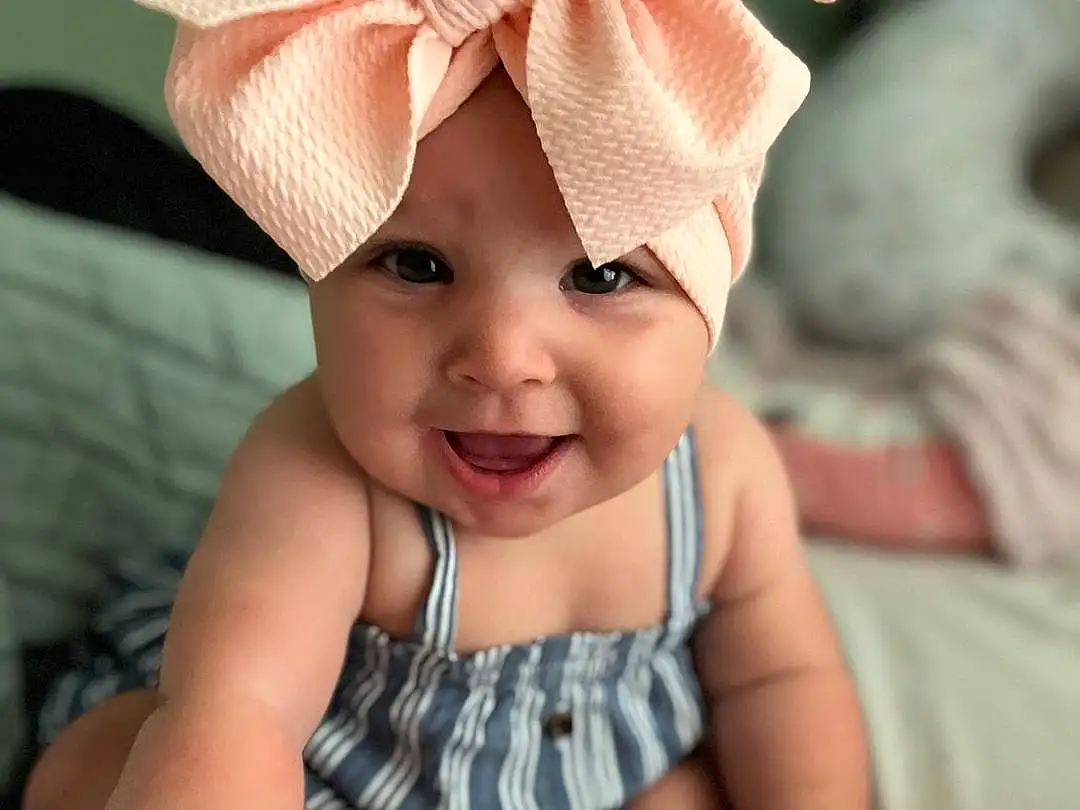 Face, Skin, Head, Smile, Chin, Photograph, White, Baby & Toddler Clothing, Human Body, Textile, Sleeve, Happy, Pink, Finger, Baby, Toddler, Comfort, Cap, Headpiece, Headband, Person, Joy, Headwear
