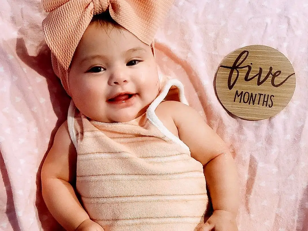 Face, Skin, Smile, Sleeve, Happy, Gesture, Baby & Toddler Clothing, Pink, Baby, Finger, Toddler, Pattern, Magenta, Peach, Comfort, Child, Fashion Accessory, Thigh, Linens, Person