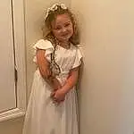 Hair, Smile, Arm, Shoulder, Dress, Sleeve, Standing, Happy, Day Dress, One-piece Garment, Embellishment, Bridal Accessory, Formal Wear, Long Hair, Toddler, Jewellery, Event, Headpiece, Blond, Gown, Person, Joy