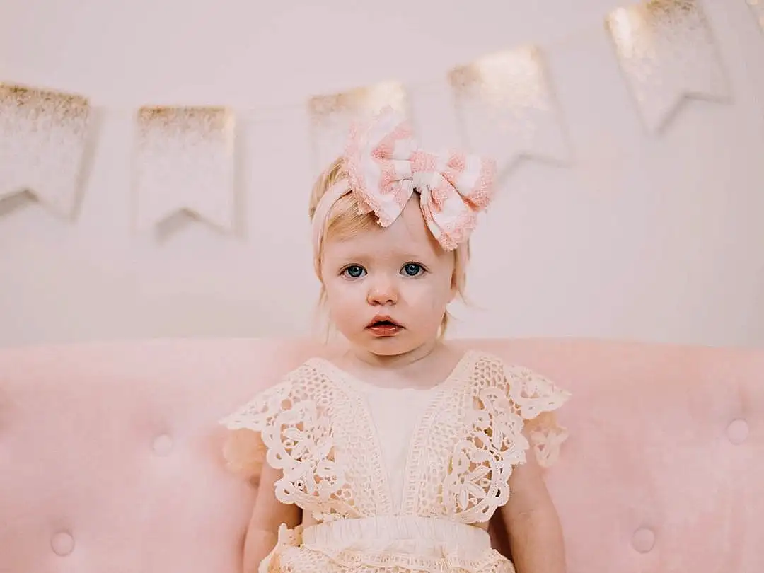 Face, Eyes, Baby & Toddler Clothing, Flash Photography, Sleeve, Dress, Iris, Happy, Pink, Headpiece, Toddler, Embellishment, Headband, Baby, Wood, Sitting, Jewellery, Fashion Accessory, Hair Accessory, Person, Headwear