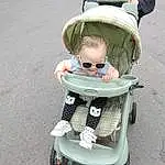 Wheel, Tire, Baby Carriage, Sunglasses, Toddler, Baby, Baby & Toddler Clothing, Cap, Child, Baby Products, Personal Protective Equipment, Eyewear, Sitting, Fun, Asphalt, Smile, Toy, Person