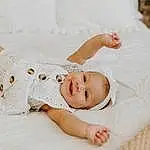 Skin, Smile, Eyes, Facial Expression, White, Comfort, Flash Photography, Textile, Sleeve, Happy, Dress, Baby & Toddler Clothing, Toddler, Baby, Child, Linens, Bridal Accessory, Headpiece, Wedding Dress, Person, Joy