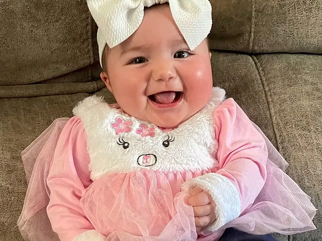 Smile, Cheek, Head, Eyes, Baby & Toddler Clothing, Sleeve, Happy, Pink, Toddler, Costume Hat, Baby, Child, Headpiece, Grass, Headband, Fashion Accessory, Hair Accessory, Magenta, Sitting, Laugh, Person, Joy, Headwear