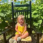 Smile, Plant, Cloud, Sky, People In Nature, Botany, Nature, Grass, Yellow, Baby & Toddler Clothing, Happy, Outdoor Furniture, Toddler, Leisure, Summer, Fence, Recreation, Sandal, Sitting, Fun, Person, Joy
