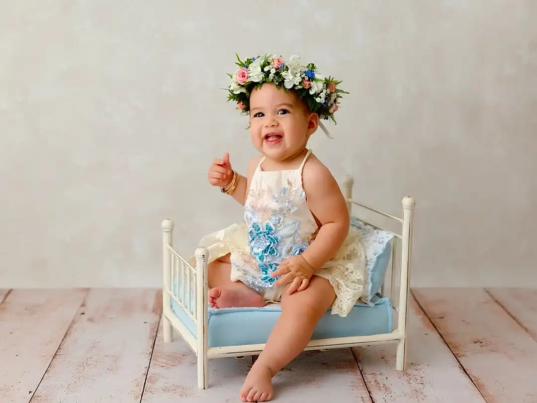 Face, Skin, Head, Smile, Eyes, Flash Photography, Happy, Flower, Baby & Toddler Clothing, Headgear, Headpiece, Plant, Baby, Toddler, Grass, Headband, Wood, Chair, Jewellery, Child, Person, Headwear