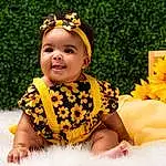 Plant, Flower, Smile, Facial Expression, Leaf, Happy, Baby & Toddler Clothing, Dress, Yellow, People In Nature, Toddler, Grass, Fun, Petal, Leisure, Child, Baby, Event, Headpiece, Spring, Person, Headwear