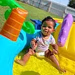 Photograph, Green, Blue, Sky, Outdoor Recreation, Happy, Yellow, Leisure, Playground, Fun, Toddler, Smile, Grass, Chute, Baby & Toddler Clothing, Outdoor Play Equipment, Recreation, Child, T-shirt, Inflatable, Person