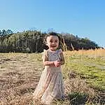 Face, Hair, Sky, Head, Plant, People In Nature, Dress, Sleeve, Happy, Tree, One-piece Garment, Grass, Grassland, Toddler, Meadow, Fun, Day Dress, Landscape, Prairie, Person, Joy