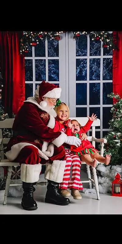 Smile, Photograph, Leg, Window, Hat, Santa Claus, Plant, Red, Lap, Christmas Tree, Curtain, Toddler, People, Fun, Happy, Tree, Christmas Decoration, Christmas Ornament, Event, Person, Joy, Headwear