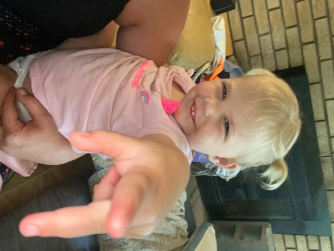 Nose, Head, Hand, Smile, Hairstyle, Mouth, Gesture, Dress, Finger, Happy, Toddler, Fun, Thumb, Nail, Child, Baby, Sunglasses, Event, Chest, Eyewear, Person, Joy