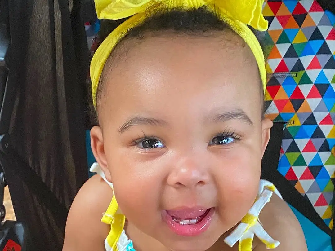 Nose, Cheek, Skin, Smile, Lip, Chin, Eyebrow, Facial Expression, Mouth, Yellow, Happy, Toddler, Fun, Baby Laughing, Child, Baby, Baby & Toddler Clothing, Leisure, Vehicle Door, Car Seat, Person, Joy
