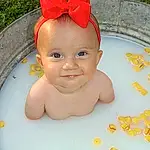 Face, Skin, Water, Eyes, Smile, Fluid, Baby, Baby Bathing, Toddler, Happy, Bathing, Child, Fun, Baby Products, Leisure, Bath Toy, Fashion Accessory, Headpiece, Costume Hat, Circle, Person, Joy