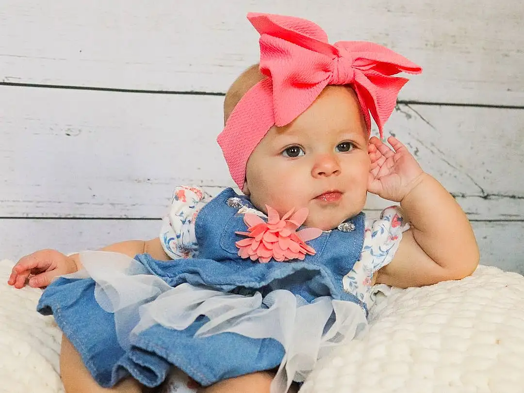 Face, Skin, Baby & Toddler Clothing, Textile, Baby, Pink, Happy, Toddler, Fun, Pattern, Grass, Headpiece, Sitting, Magenta, Fashion Accessory, Costume Hat, Child, Leisure, Peach, Costume, Person, Headwear