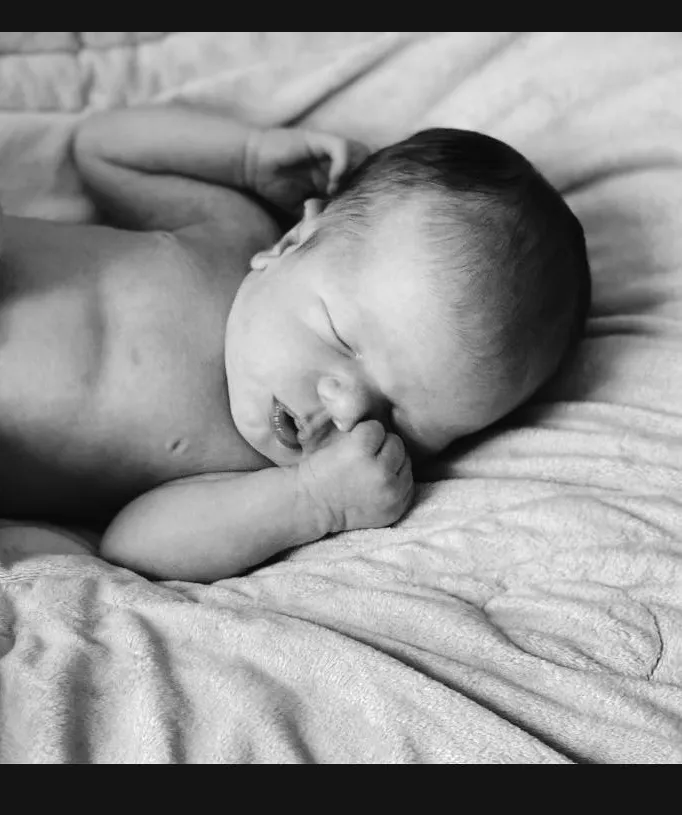 Forehead, Nose, Cheek, Skin, Head, Arm, Mouth, Comfort, Human Body, Baby, Gesture, Toddler, Happy, Flash Photography, Linens, Black & White, Child, Monochrome, Bedtime, Smile, Person