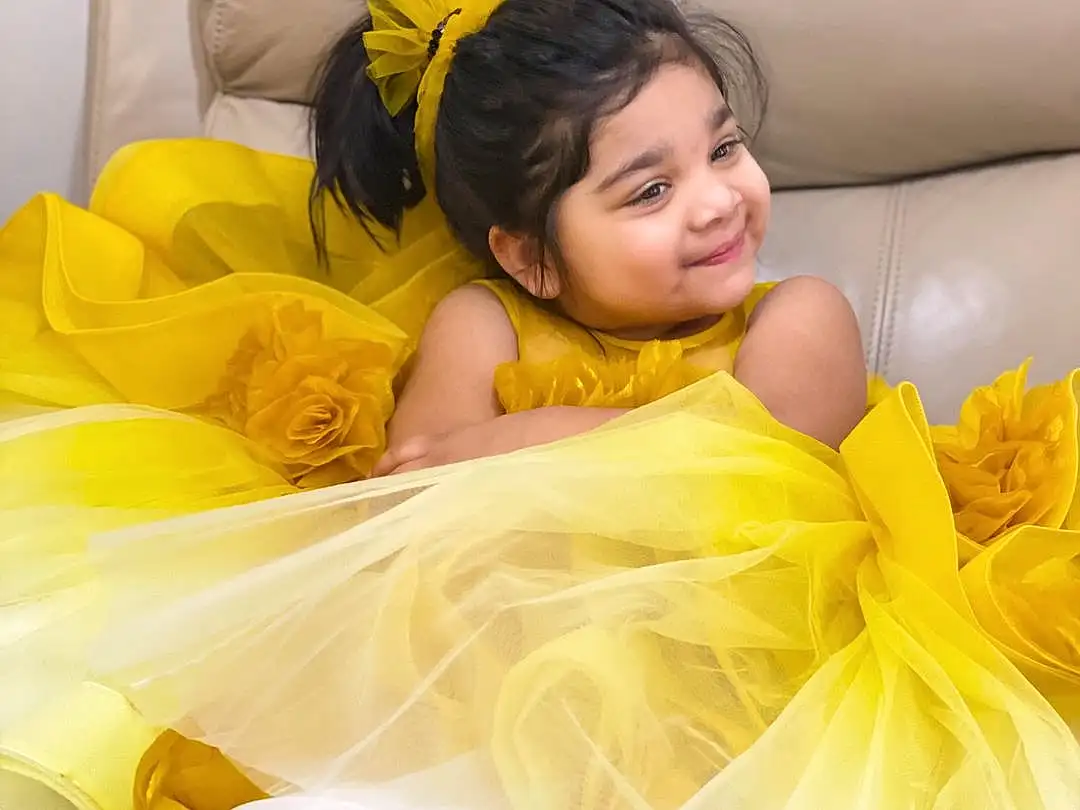 Face, Hair, Head, Furniture, Arm, Eyes, White, Couch, Comfort, Textile, Fashion, Yellow, Happy, Flash Photography, Dress, Black Hair, Linens, Child, Bedding, Leisure, Person, Joy