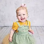 Clothing, Smile, Skin, Outerwear, Dress, Facial Expression, One-piece Garment, Baby & Toddler Clothing, Sleeve, Happy, Standing, Baby, Pink, Day Dress, Toddler, Child, Pattern, Wood, Magenta, Blond, Person, Joy