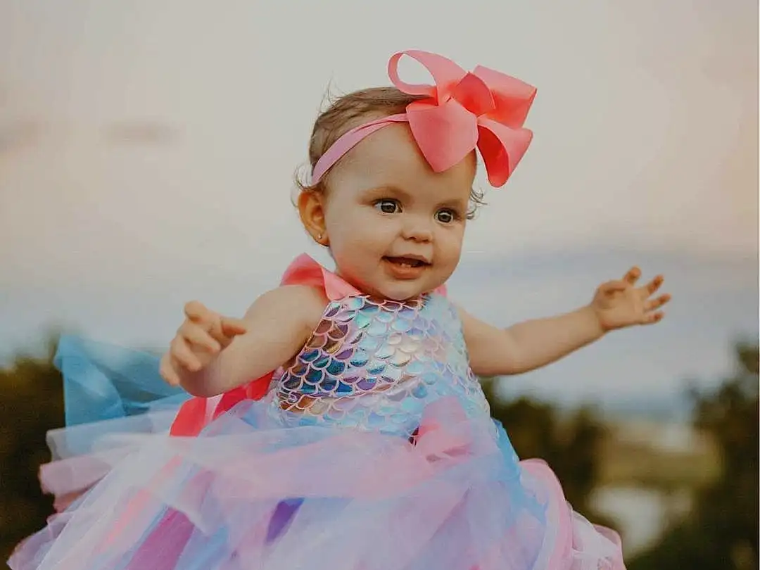 Skin, Smile, Facial Expression, Flash Photography, Happy, Baby & Toddler Clothing, Gesture, Dress, Pink, Dance, Fun, Toddler, Day Dress, Child, Headpiece, Magenta, Event, Entertainment, Headband, Fashion Design, Person, Headwear