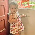 Joint, Skin, Hairstyle, Shoulder, One-piece Garment, Neck, Sleeve, Dress, Standing, Gesture, Day Dress, Finger, Baby & Toddler Clothing, Waist, Toddler, Door, Happy, Thigh, Pattern, Person