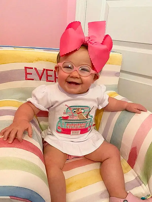 Smile, White, Shorts, Baby & Toddler Clothing, Happy, Pink, Thigh, Comfort, Toddler, Baby, Thumb, Fun, Party Supply, Lap, Knee, Human Leg, Child, Event, Room, Sitting, Person, Joy, Headwear