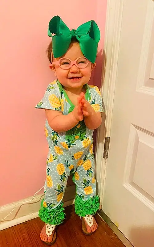 Clothing, Head, Smile, Outerwear, Hairstyle, Green, Baby & Toddler Clothing, Sleeve, Active Pants, Door, Yellow, Pink, Happy, Toddler, Cool, T-shirt, Personal Protective Equipment, Pattern, Costume Hat, Baby, Person, Joy