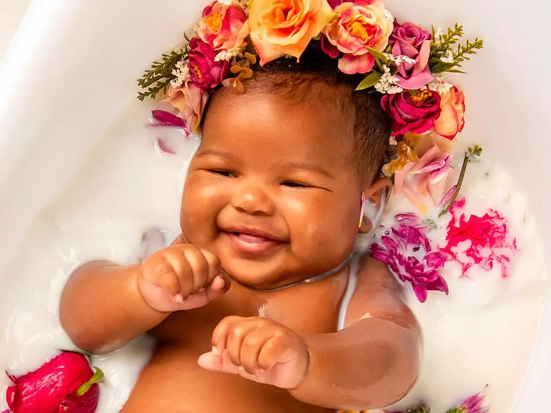 Face, Skin, Head, Smile, Lip, Hand, Flower, Arm, Happy, Gesture, Pink, Finger, Baby, Petal, Toddler, Chest, Nail, Trunk, Abdomen, Jewellery, Person, Joy