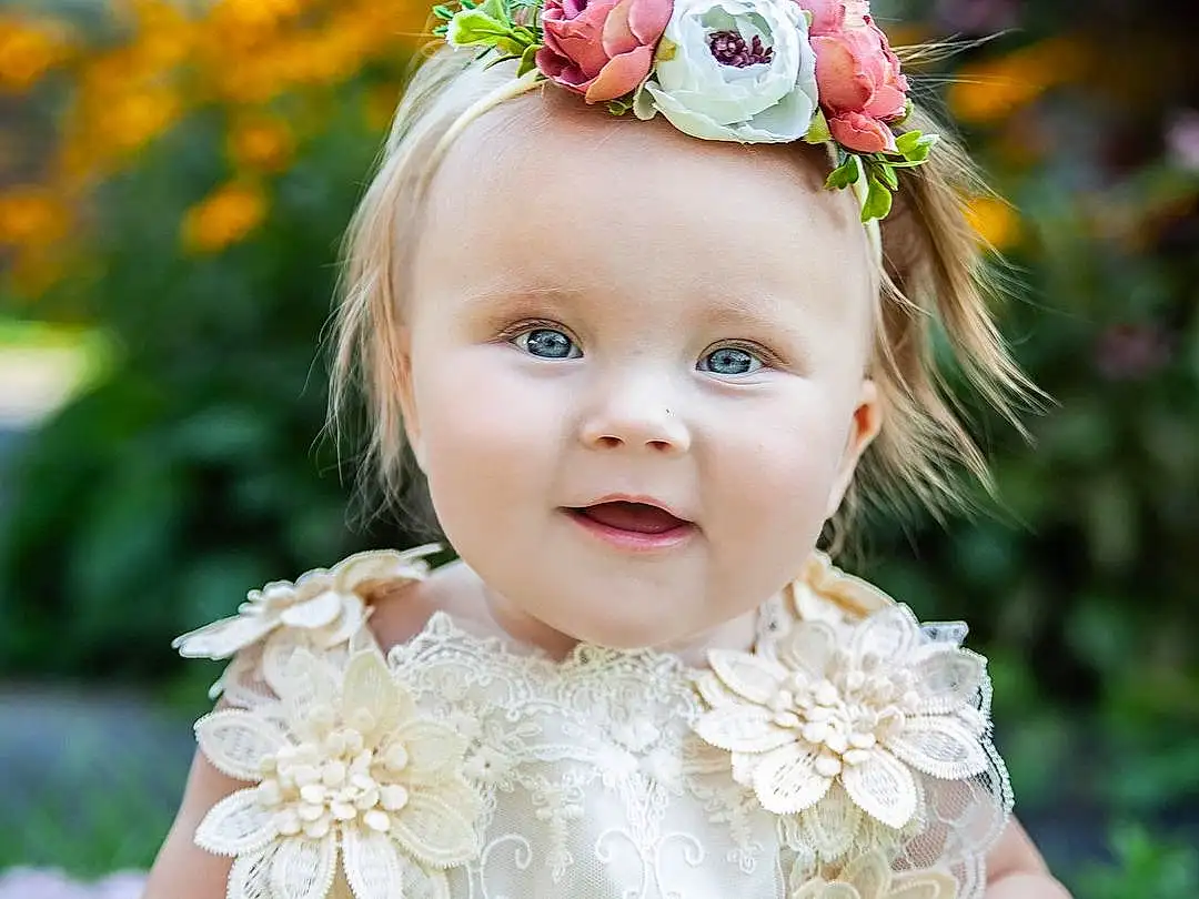 Face, Skin, Plant, Flower, Hairstyle, Photograph, Smile, Dress, Botany, Iris, Happy, Pink, Petal, Flash Photography, Baby & Toddler Clothing, Headgear, Grass, Headpiece, Toddler, Baby, Person