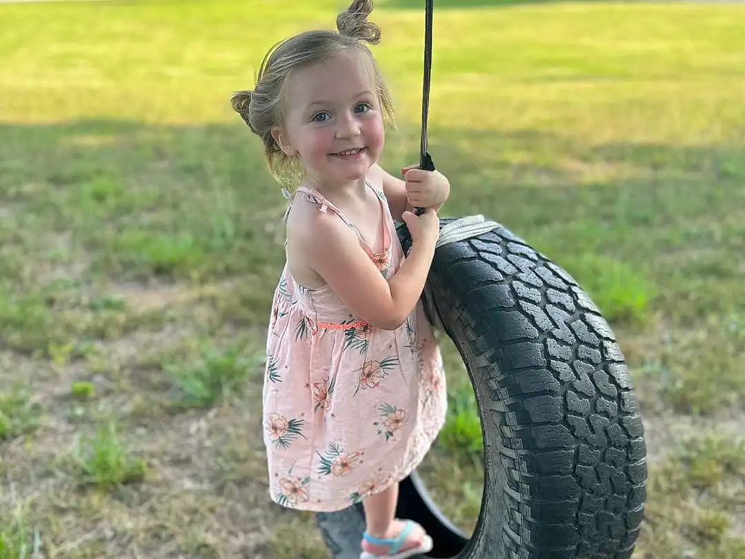 Smile, Tire, Wheel, Automotive Tire, Tread, Grass, People In Nature, Synthetic Rubber, Happy, Toddler, Swing, Baby & Toddler Clothing, Fun, Leisure, Rim, Lawn, Tire Care, Grassland, Automotive Wheel System, Bicycle Tire, Person, Joy