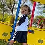 Footwear, Shoe, Shorts, Yellow, Tree, Grass, Sneakers, Leisure, T-shirt, Recreation, Happy, Fun, Outdoor Play Equipment, Playground, Toddler, City, Electric Blue, Player, Human Settlement, Child, Person